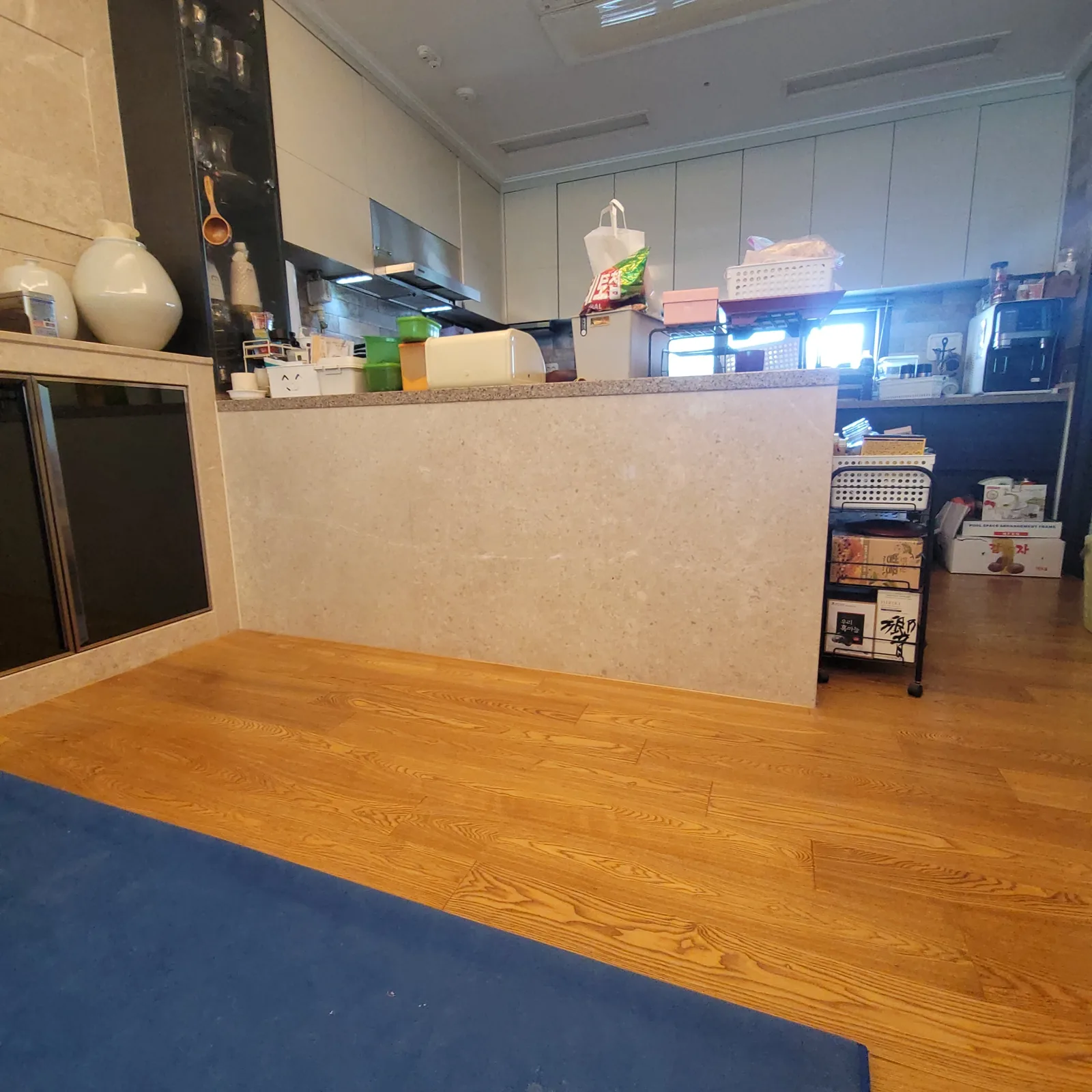 주방 아일랜드장·식탁 철거와 바닥 마감 — 거실 쪽으로 놓인 돌무늬 판재 아일랜드장